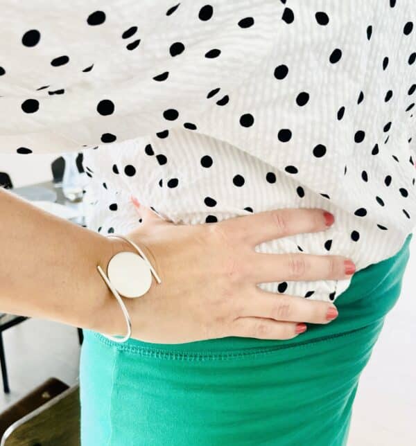 A woman waering a polka dotted shirt and green skort wearing a silver bracelet